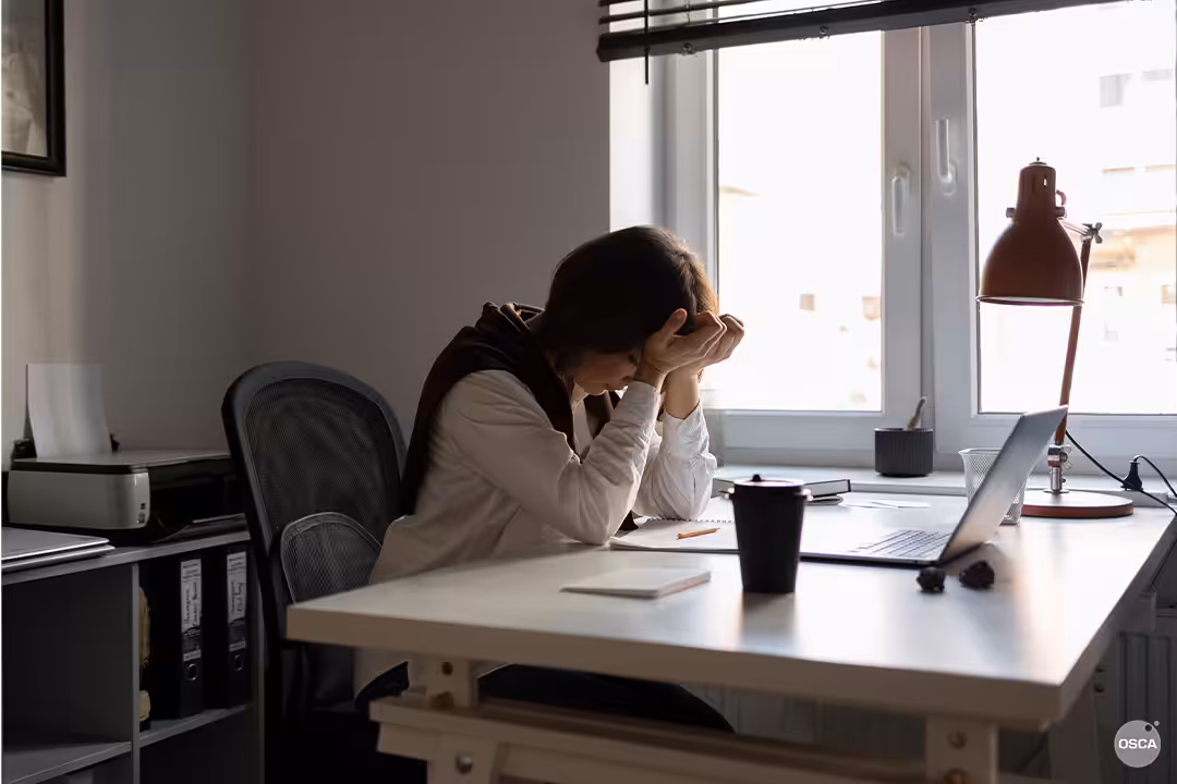 Woman sitting on office chair, hands on her forehead, seemingly exhausted and frustrated